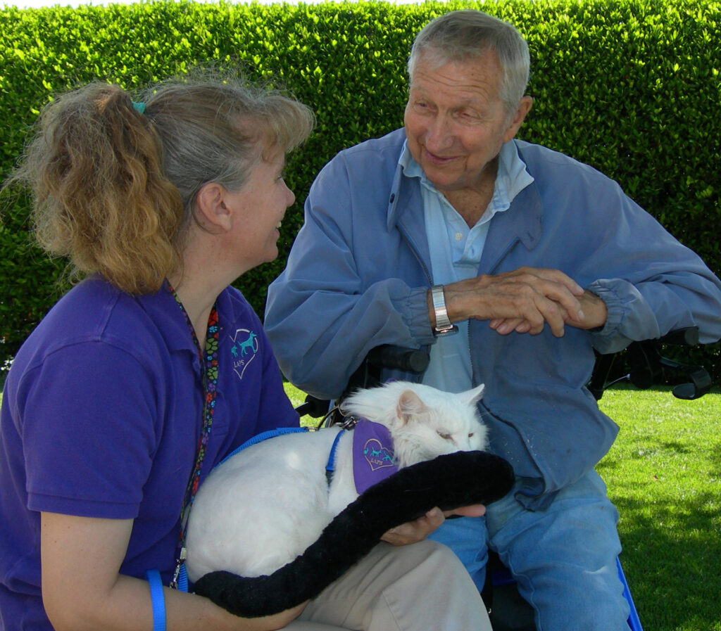 Two people smiling with a white cat