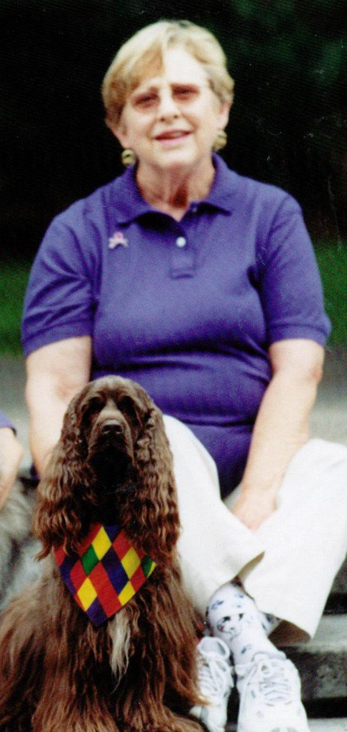 Co-founder Carolyn Lenzi sits on steps outside. In front of her is her brown cocker spaniel, Bailey. Bailey was one of LAPS first therapy dogs.